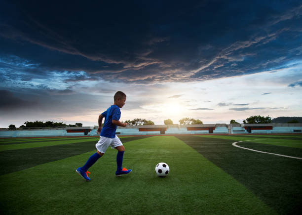 Young boy kicking a soccer ball on the field