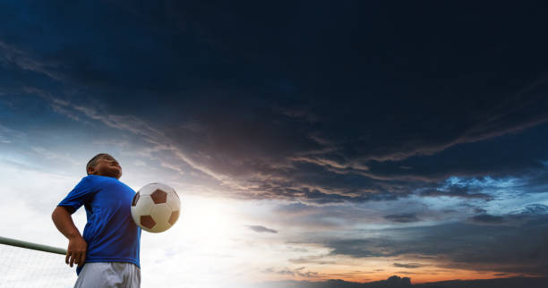 istock Young asian boy hitting soccer ball with chest 1444348014
