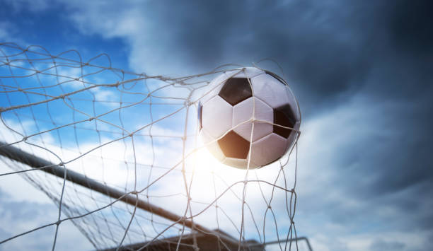 футбольный мяч попадает в сетку с драматическим небом - soccer goal net winning стоковые фото и изображения