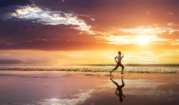 istock Asian young man running on the beach at sunset 1444348049