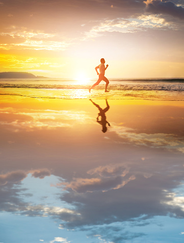 Asian young man running on the beach at sunset