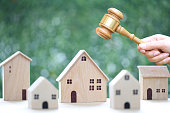 Property auction, Woman hand holding gavel wooden and model house on natural green background, lawyer of home real estate and ownership property concept
