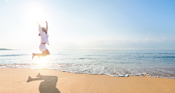 Excited young woman jumping at the beach