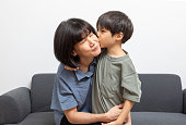 Asian woman cuddling her little son smile and look at camera.
