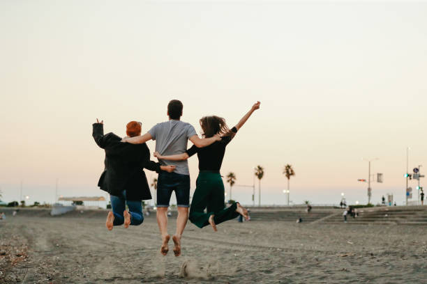Free and Easy Friends Jumping for Joy at the Beach stock photo