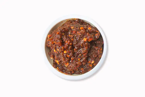 Photo of Roasted Chili Paste Set (Nam Prik Pao) on a white plate and white background. Top view, isolate