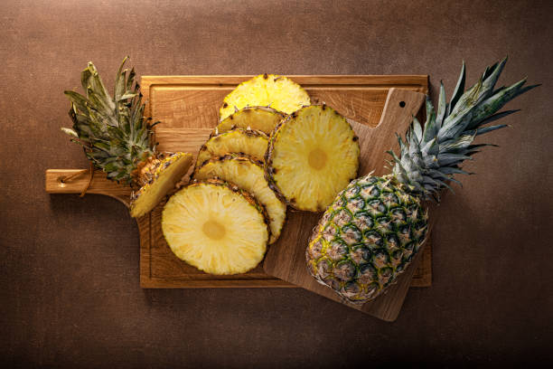 Pineapple. Sliced and whole pineapple on brown background, top vew Pineapple. Sliced and whole pineapple on brown background, top vew pineapple stock pictures, royalty-free photos & images