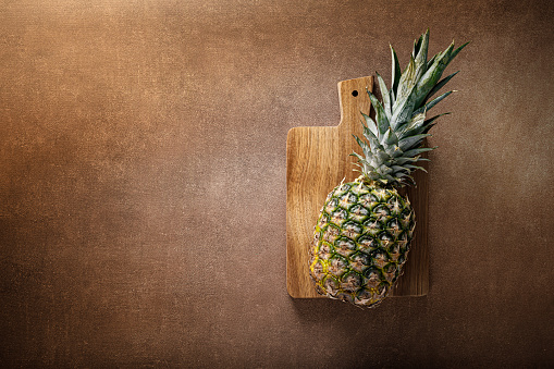 Pineapple. Whole pineapple on brown background, top vew