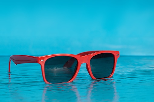 Glasses in the water, blue tropical beach. Copy space, no people