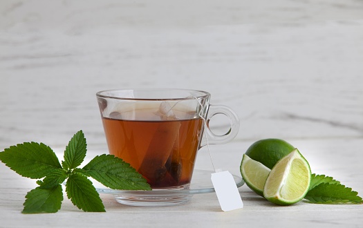 A closeup of glass of tea with lime in white background