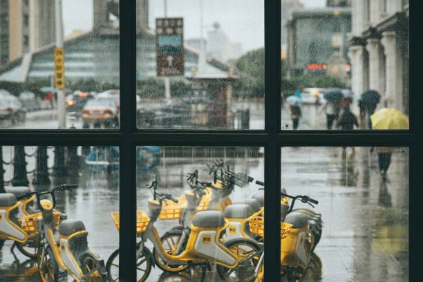 Guilin, China - October 18, 2013: Chinese men on bike with rain cover in the rain at Guilin, China.