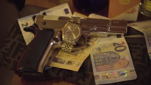 Closeup shot of a luxurious watch on a gun put on euros in HD