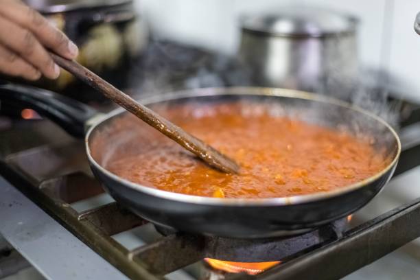 istock Man's hand holding a wooden ladle while stirring the pan with sauce 1444364497