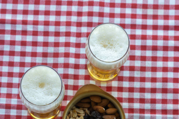 bicchiere di birra sul tavolo con una tovaglia a scacchi e snack - healthy eating eating food and drink beer nuts foto e immagini stock