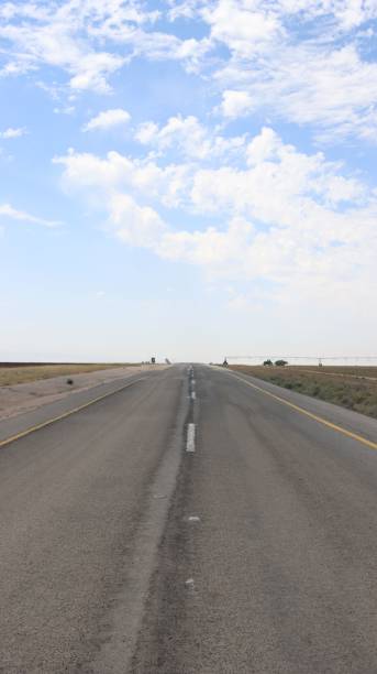 istock Vertical shot of an empty asphalt road under a cloudy blue sky 1444367872