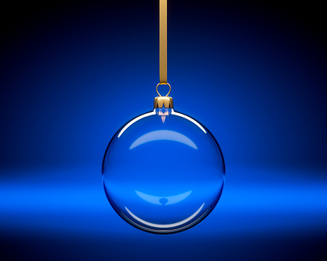 Glass Christmas Ball hanging in Front of a dark blue Background with Copy Space