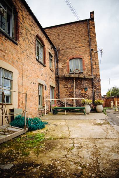 Vertical of an anchor leaned against a red brick wall at a dockyard.
