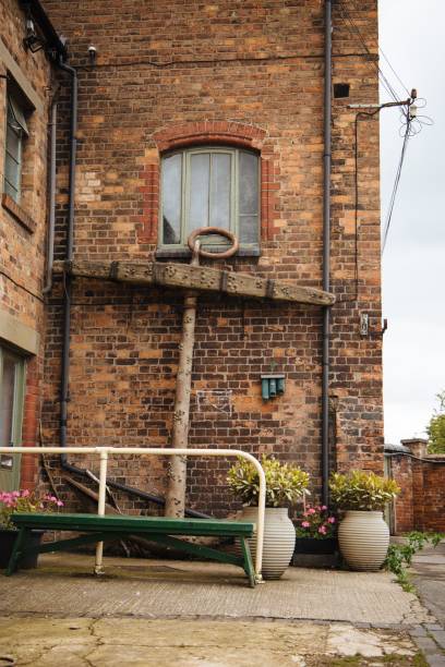 istock Vertical of an anchor leaned against a red brick wall at a dockyard. 1444368618