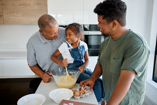 Family, love and cooking with a girl, father and grandfather baking together in the kitchen of their home. Food, learning and teaching with a daughter, dad and grandad preparing a meal in a house