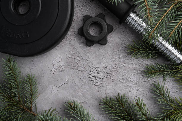 istock Winter flat lay composition frame for Christmas, with gym dumbbells barbell weight plate, tree branches and copy space. 1444369058