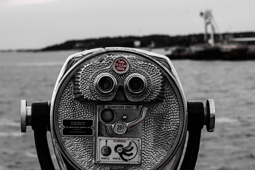 A grayscale of a coin-operated binocular at a shore