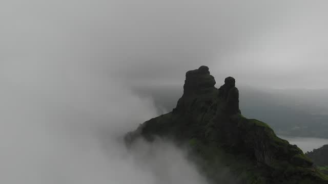 Aerial footage of a rock formation in a rural area in cloudy sky background