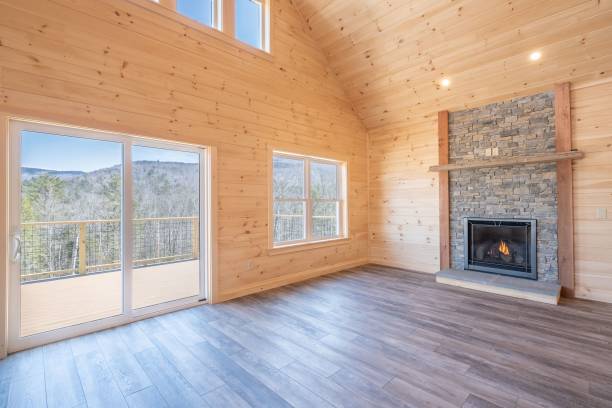 istock Empty room interior with wooden walls, windows, a laminate floor, and a fireplace 1444379843