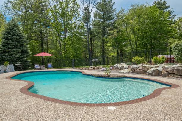 istock Outdoor pool around chairs and an umbrella surrounded by tall trees 1444380103