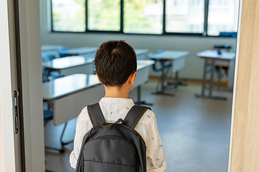 Schoolboy with backpack entering to classroom
