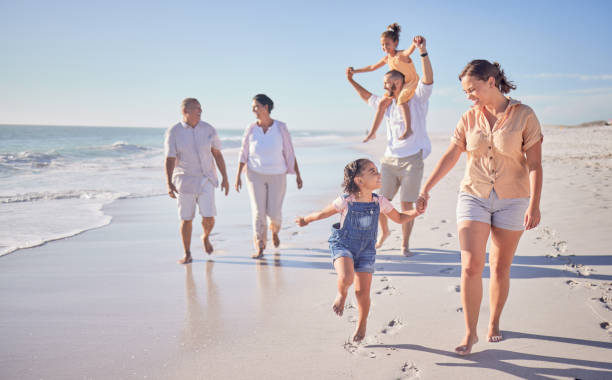 família, praia e feliz em férias de cancun no verão com sorriso, riso e amor juntos andando na areia. rir, criar laços e perseguir a alegria enquanto homens, mulheres e crianças brincam em viagens de férias - couple mature adult action walking - fotografias e filmes do acervo