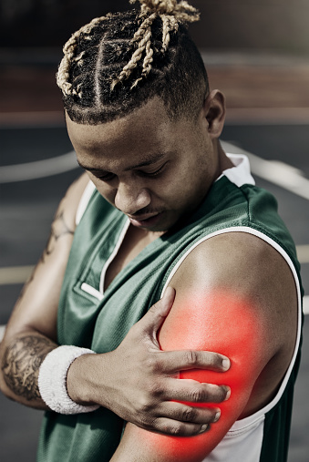 Fitness, basketball and black man with sports injury in need of first aid or physiotherapy during game. Sportsman from Nigeria with hand on arm, muscle pain and medical emergency on basketball court.