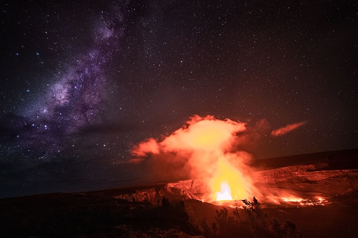 A scenic view of a steaming Kilauea volcano under a beautiful starry night sky on Big Island, Hawaii