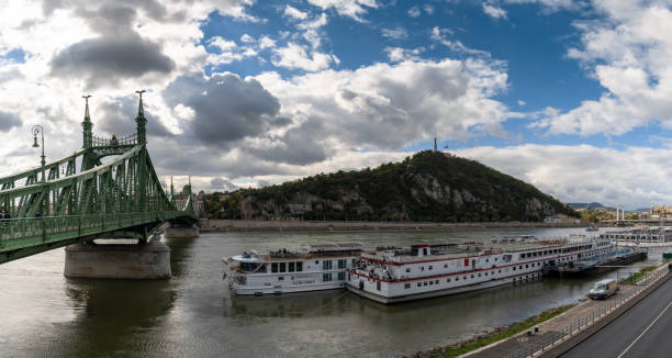 blick auf flusskreuzfahrtschiffe auf der donau in budapest mit der freiheitsbrücke - budapest danube river river hungary stock-fotos und bilder