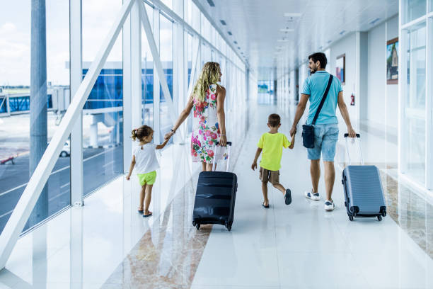istock Back view of a family talking while walking through airport hallway. 1444385914