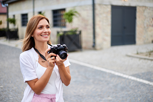 Young woman on city street taking photos with camera