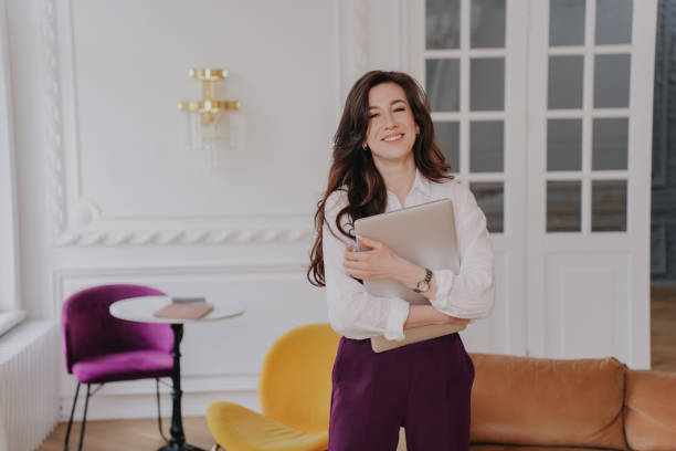istock Cheerful young woman embracing laptop happily at home, finished her work. Brunette pretty entrepreneur looking aside being in good mood. Satisfied student glad to receive great news. Remote education. 1444389708