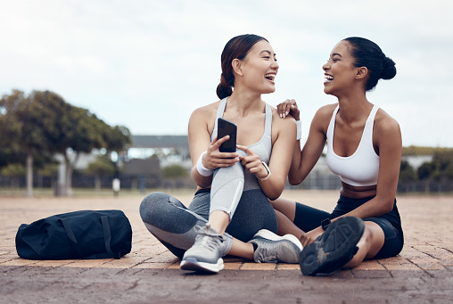 Phone, fitness and women on social media in the city of London after workout together in the street. Happy, smile and healthy athlete friends with funny mobile app on tech after training in the road
