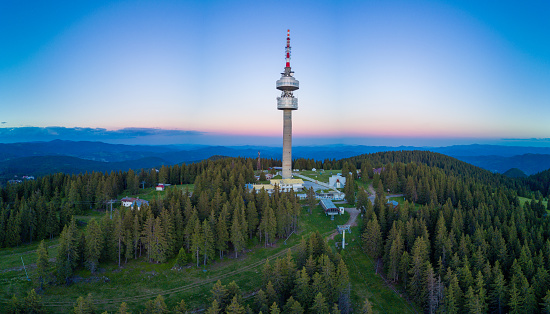 High telecommunications famous Snezhanka tower in the valley of the Rhodope mountains and forests against a cloudy gloomy sky. Panorama, top view