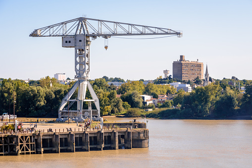Nantes, France - September 18, 2022: General view of the gray Titan crane at the tip of the island of Nantes by the Loire river with the Maison Radieuse building by Le Corbusier in the distance.