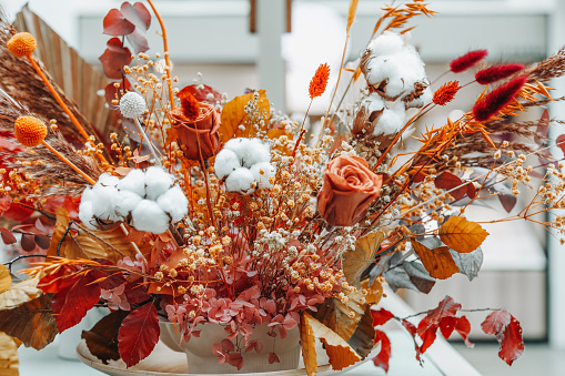 Composition of dried flowers, roses, cotton and leaves. Autumn cozy decor