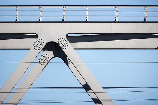 Gray steel truss bridge fragment under blue sky on a sunny day