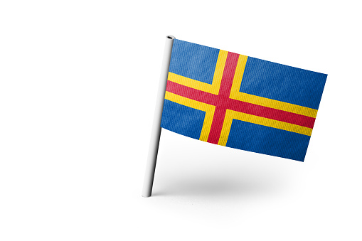 Small paper flag of Aland Islands pinned. Isolated on white background. Horizontal orientation. Close up photography. Copy space.