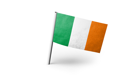 Small paper flag of Ireland pinned. Isolated on white background. Horizontal orientation. Close up photography. Copy space.