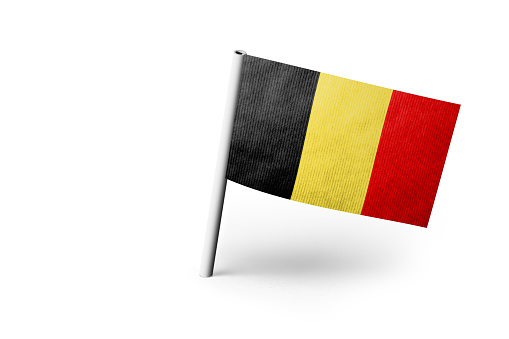 Small paper flag of Belgium pinned. Isolated on white background. Horizontal orientation. Close up photography. Copy space.