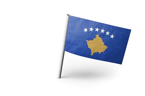 Small paper flag of Kosovo pinned. Isolated on white background. Horizontal orientation. Close up photography. Copy space.