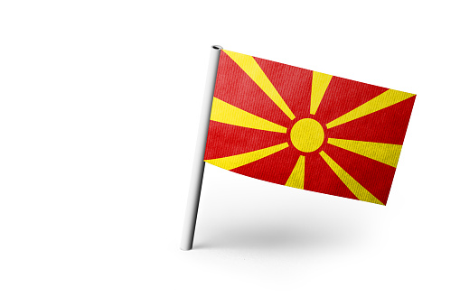 Small paper flag of North Macedonia pinned. Isolated on white background. Horizontal orientation. Close up photography. Copy space.