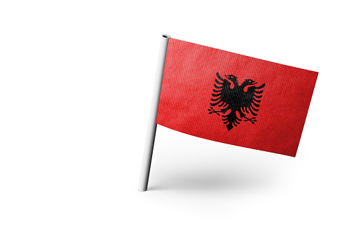 Small paper flag of Albania pinned. Isolated on white background. Horizontal orientation. Close up photography. Copy space.