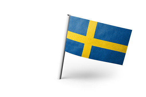 Small paper flag of Sweden pinned. Isolated on white background. Horizontal orientation. Close up photography. Copy space.