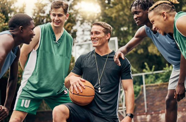 basketballtrainer im gespräch mit seinem team während einer trainingseinheit auf dem außenplatz. teamwork, motivation und inspiration rede vom trainer für basketballmannschaft spaß haben und lernen in einem sportspiel - sportsman competitive sport professional sport team sport stock-fotos und bilder