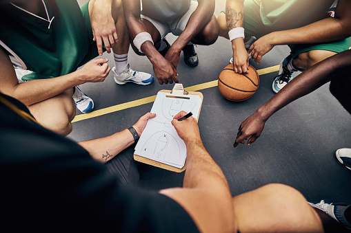 Portrait of confident basketball coach holding ball while standing in court